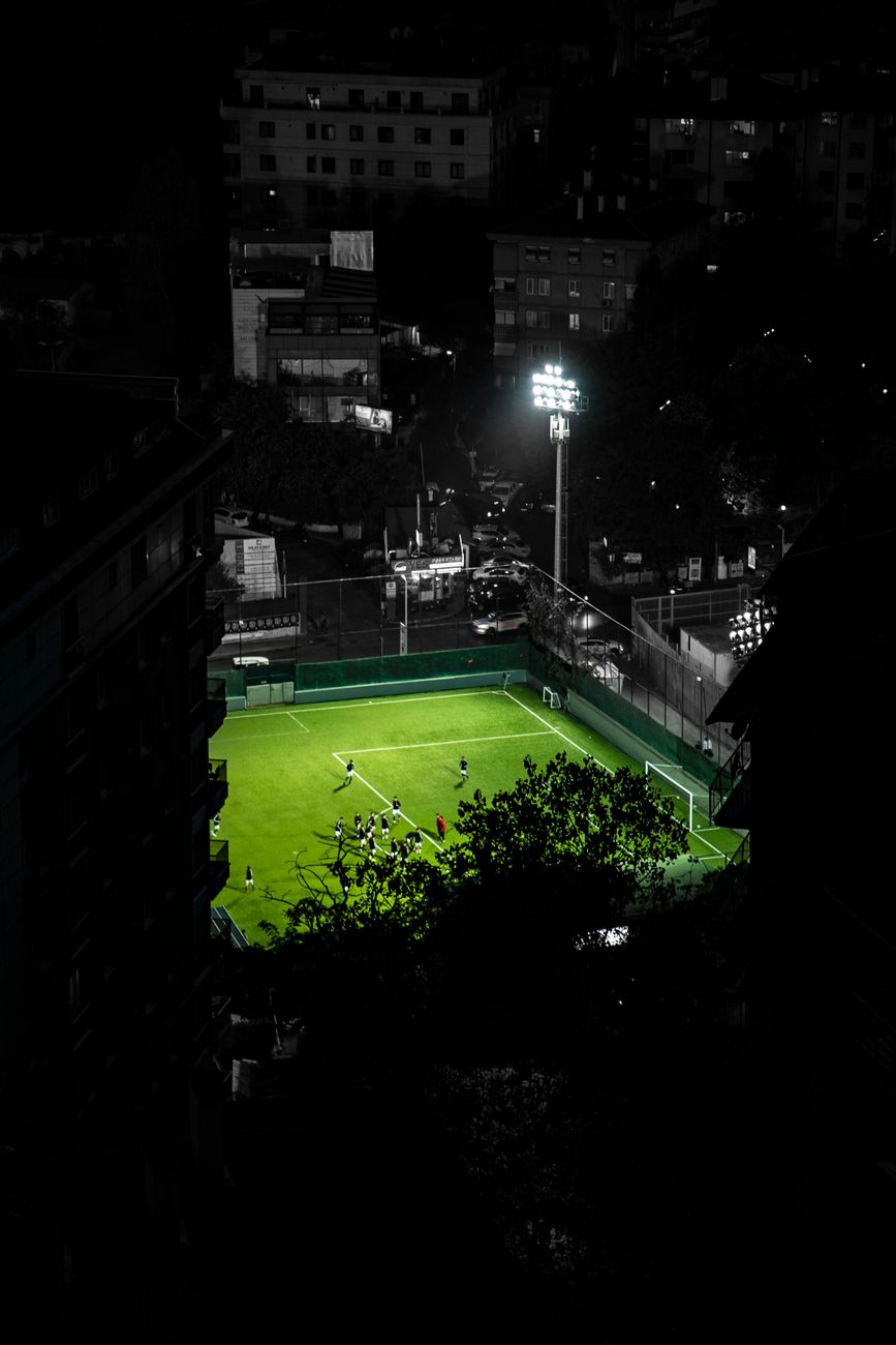 A captivating aerial shot of an illuminated soccer field in downtown Istanbul at night.